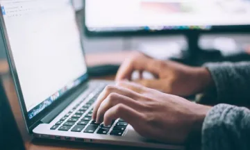 Stock image of hands typing on laptop.
