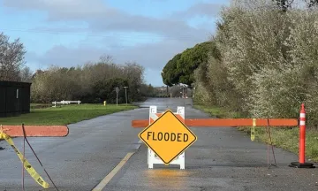 Road with a barricades and a sign that says "flooded"