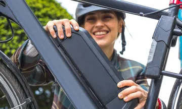 woman holding an electric bike battery mounted on frame