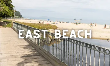 Photo of the footbridge over Sycamore Creek on East Beach with text "East Beach" overlaid