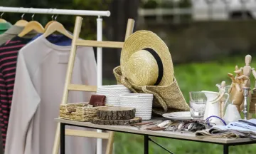 clothing, accessories and housewares on a table  for a yard sale.