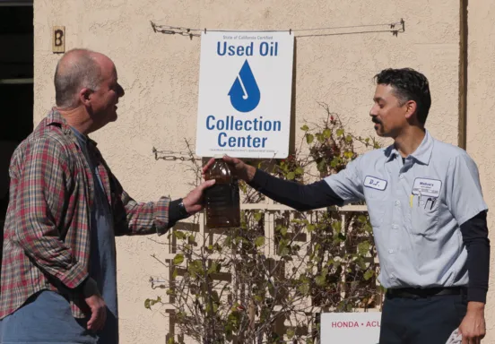 A community member returns motor oil to a Used Oil Collection Center