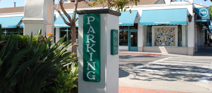 Entrance sign at Parking Lot 12 in Downtown Santa Barbara with businesses in the background