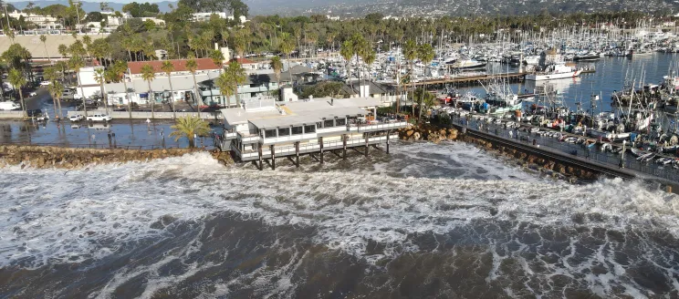 Aerial view of waves damaging Yacht Club and flooding parking lot