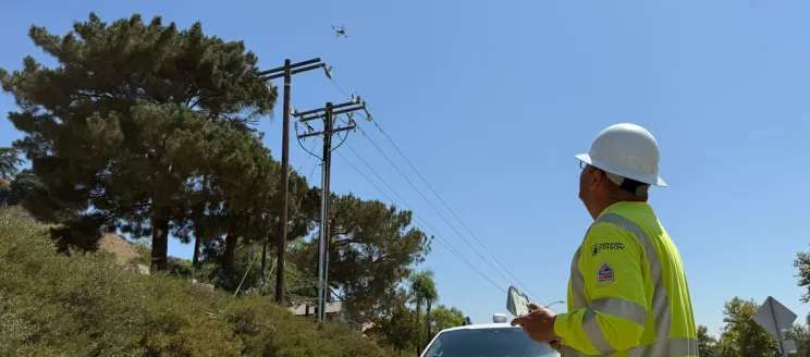 Inspector flying drone over electrical poles