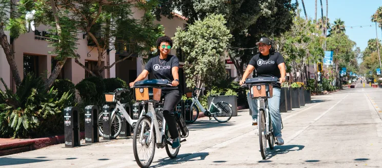 Two people riding BCycle e-bikes on State Street in Santa Barbara