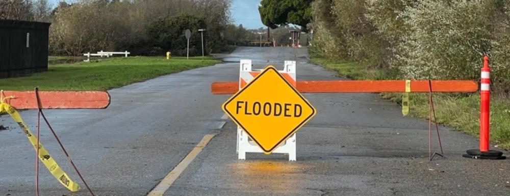 Road with a barricades and a sign that says "flooded"