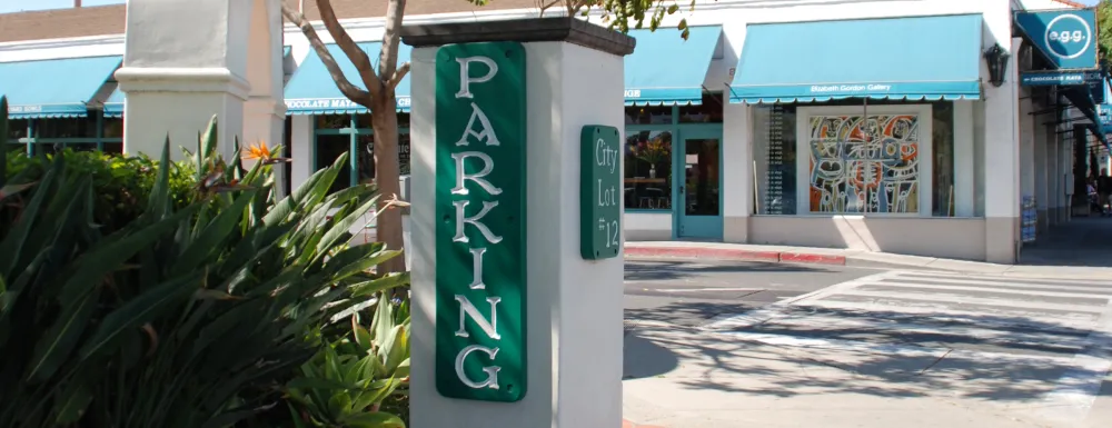 Entrance sign at Parking Lot 12 in Downtown Santa Barbara with businesses in the background