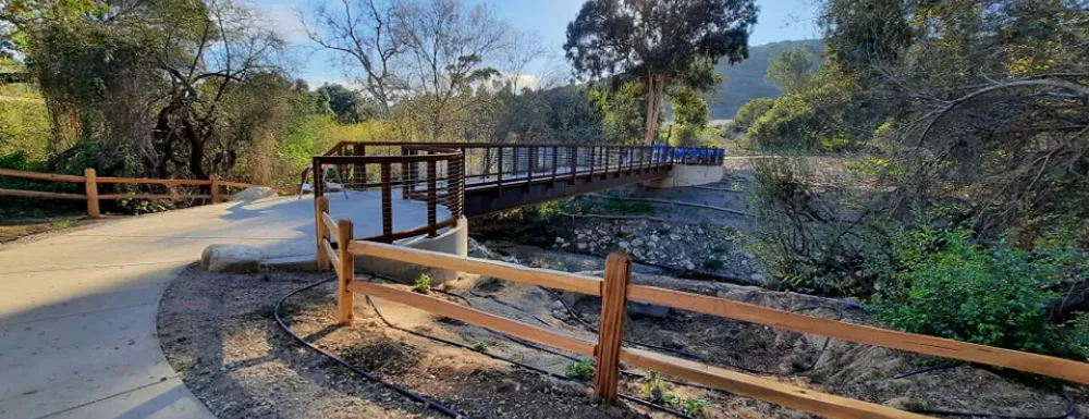 Footbridge at Arroyo Burro Open Space with sun behind trees.