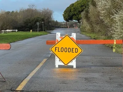 Road with a barricades and a sign that says "flooded"