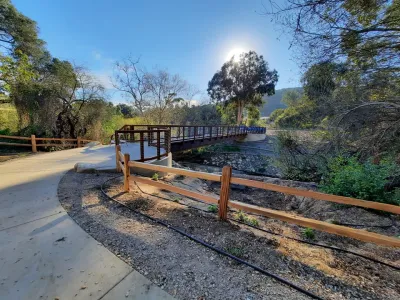 Footbridge at Arroyo Burro Open Space with sun behind trees.